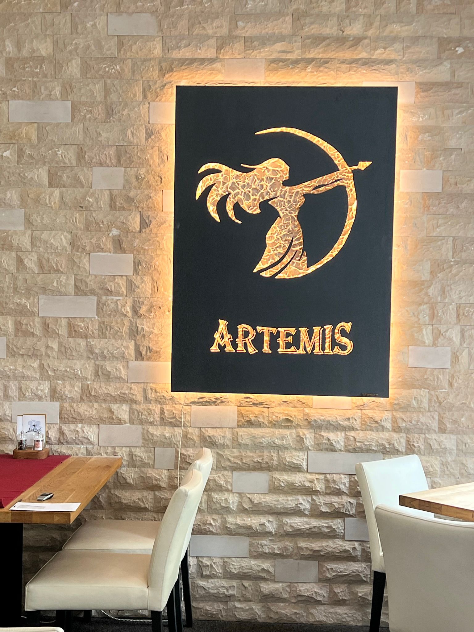 Logokunstwerk in Mattschwarz mit Logo Gold Deluxe, beleuchtet, im Restaurant