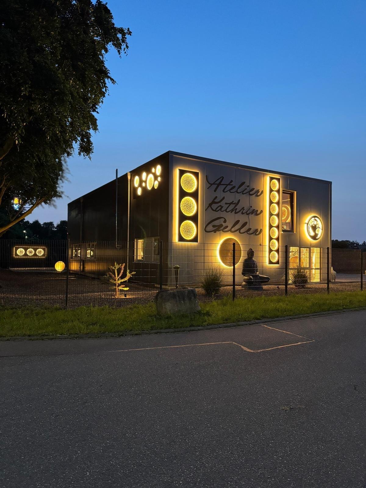 Das Atelier Kathrin Geller in Busdorf am Abend, beleuchtete Kunstwerke an der Fassade