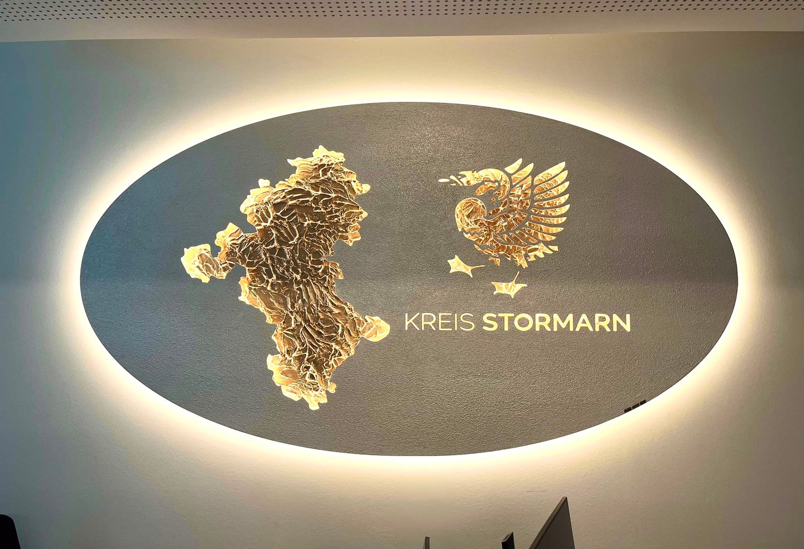 Logokunstwerk mit Logo Gold, beleuchtet, im Empfang